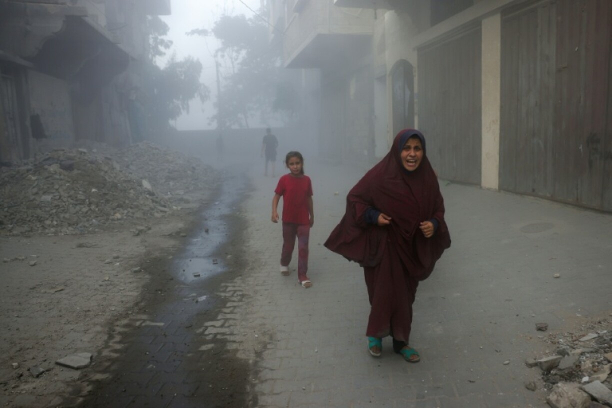 A Palestinian woman and children run from Israeli air strikes in the Saftawi neighborhood of the northern Gaza Strip