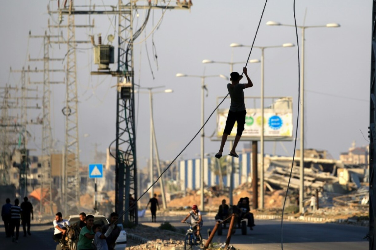 Des jeunes Palestiniens se balancent sur des câbles électriques suspendus dans le camp de réfugiés d'al-Maghazi, dans le centre de la bande de Gaza, le 5 juin 2024