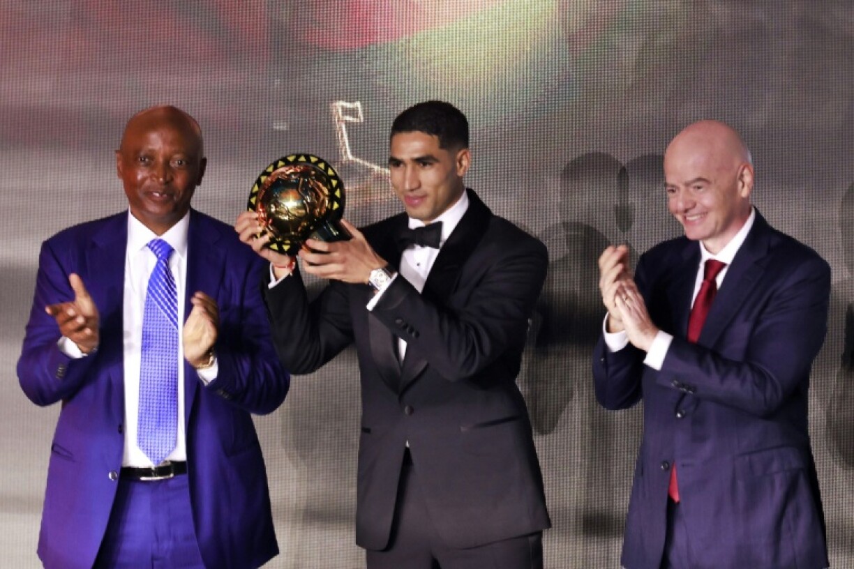 Achraf Hakimi poses with the trophy alongside CAF president Patrice Motsepe and FIFA chief Gianni Infantino