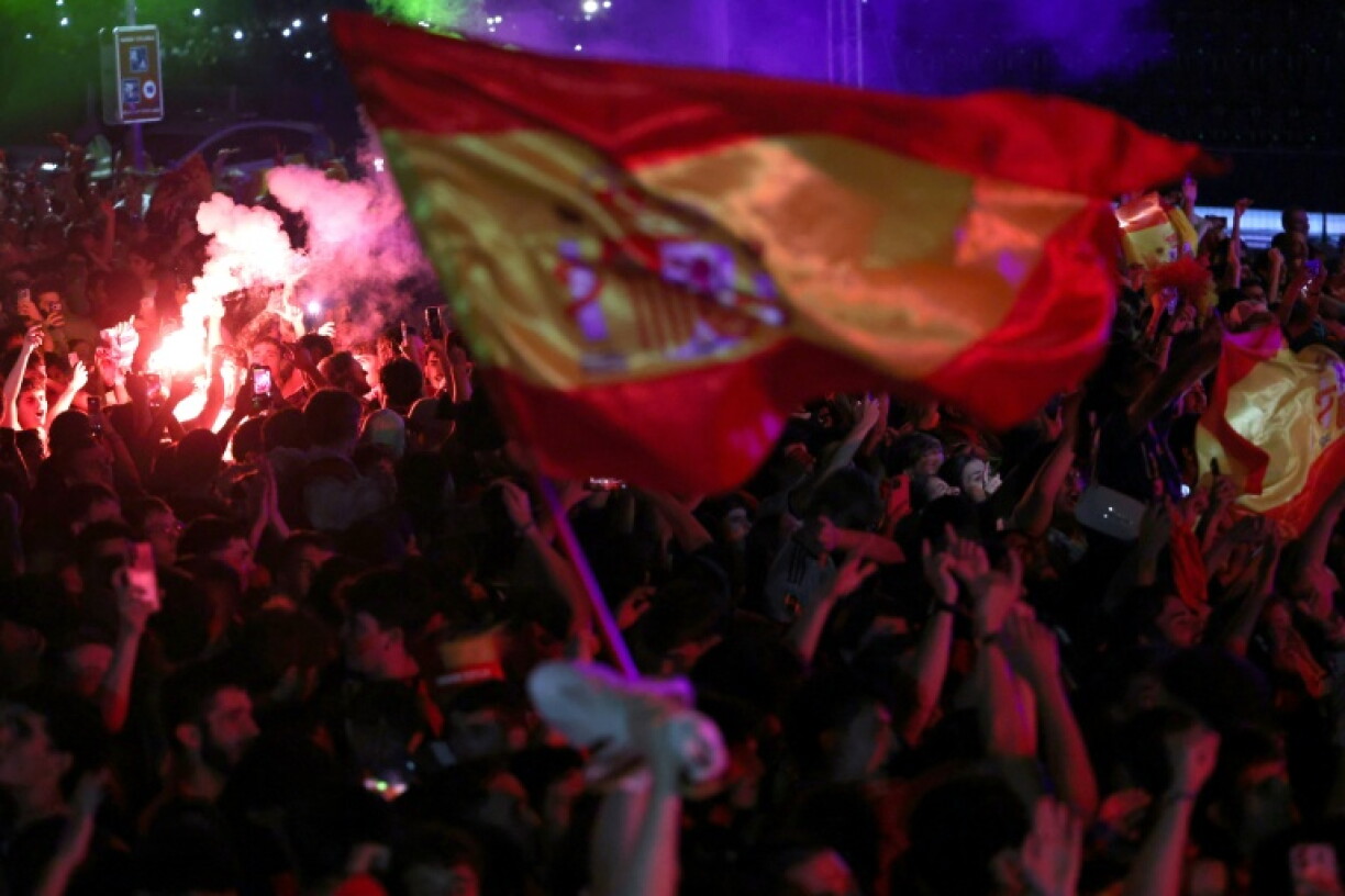 Les supporters espagnols, rassemblés sur la place Colon de Madrid le 19 juillet 2026 craquent des fumigènes et agitent des drapeaux de l'Espagne après le sacre de la Roja au Mondial