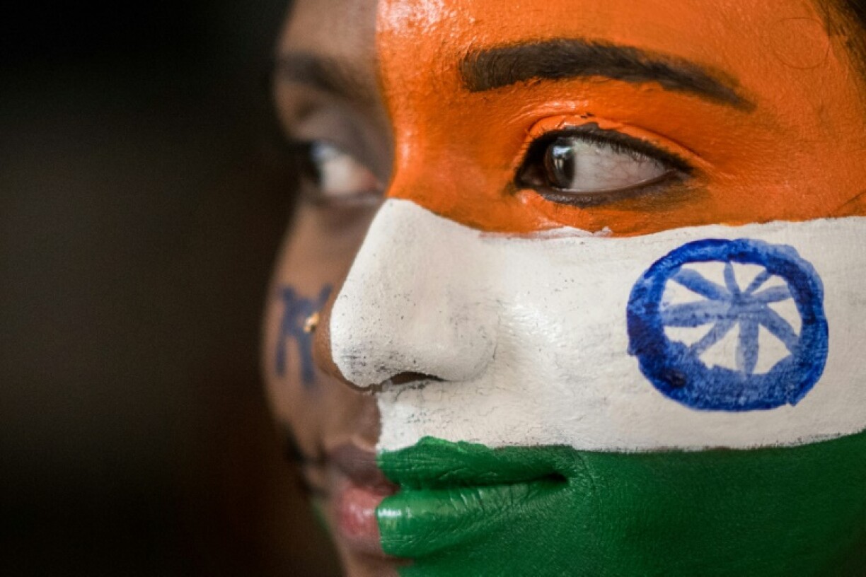 A Indian college student poses with her face painted in the colours of the national flag