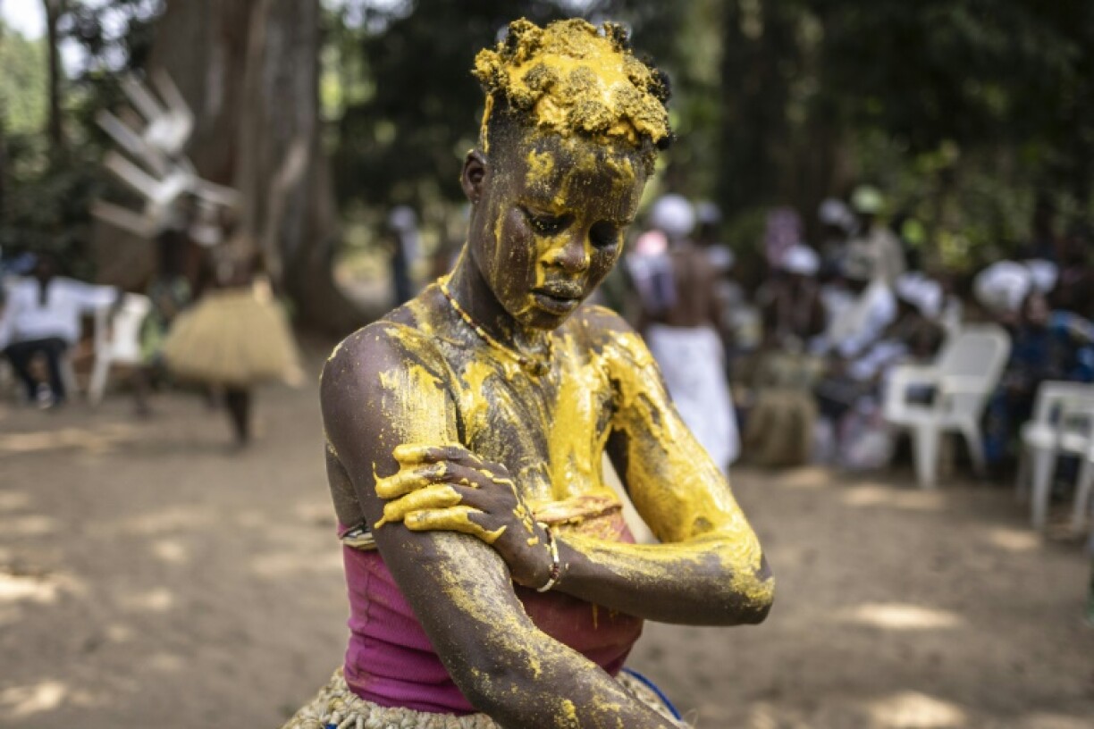 An initiate Kokou, a traditional warrior deity, covers herself with a mixture of red vegetable oil mixed with corn flour as festivities get under way