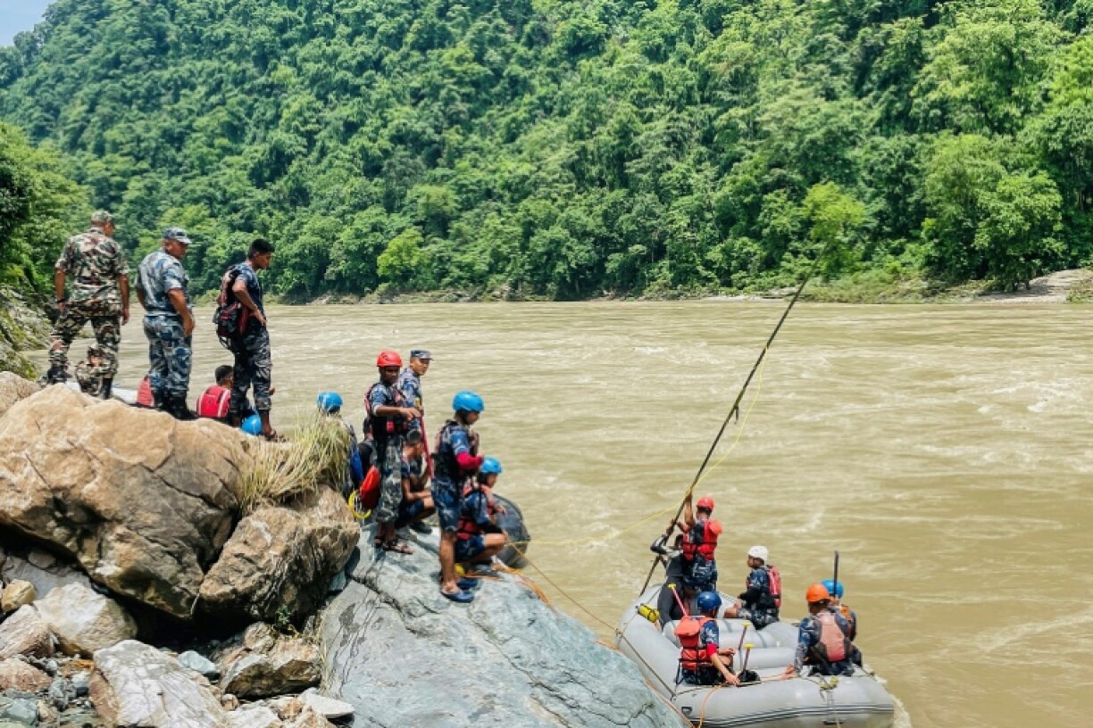 Des membres de la police armée recherchent des survivants dans la rivière Trishuli après un glissement de terrain qui a emporté deux bus, le 13 juillet 2024 à Simaltar, au Népal