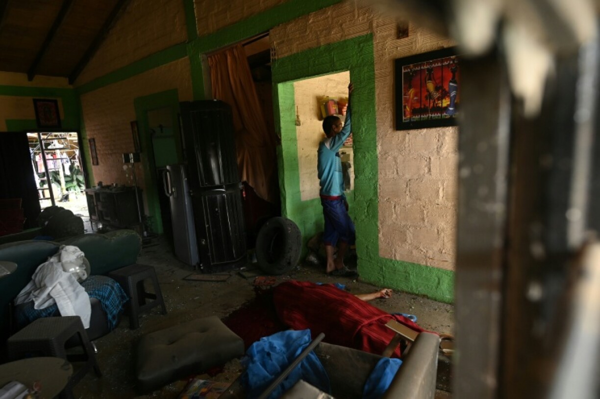 The lifeless body of one of the victims is seen next to a man inside a house after an attack with explosives in Guachinte, Valle del Cauca department, Colombia, on June 10, 2025.