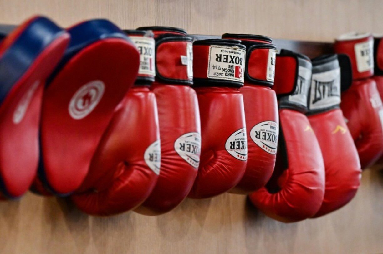 This photo taken on September 22, 2022 shows boxing gloves hanging on the wall of a gym