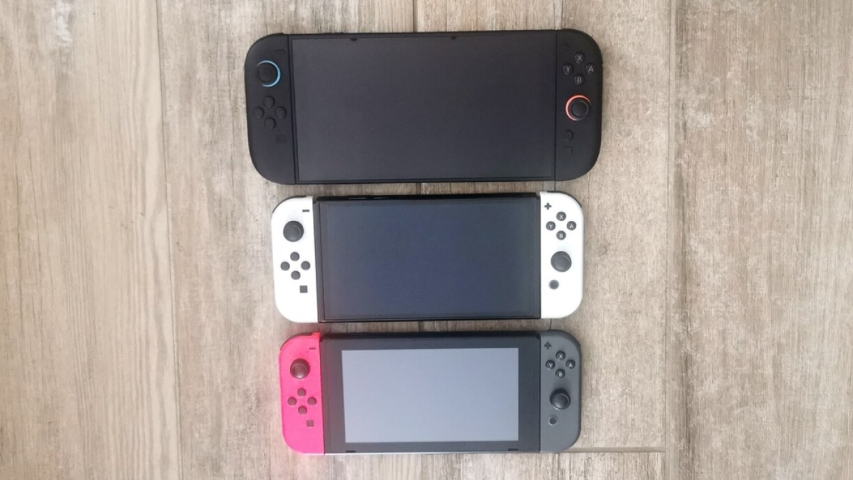 Au-dessus, la nouvelle Switch 2 s'impose par son gabarit plus grand que la Switch OLED (au milieu) et la Switch 1 (en-dessous).