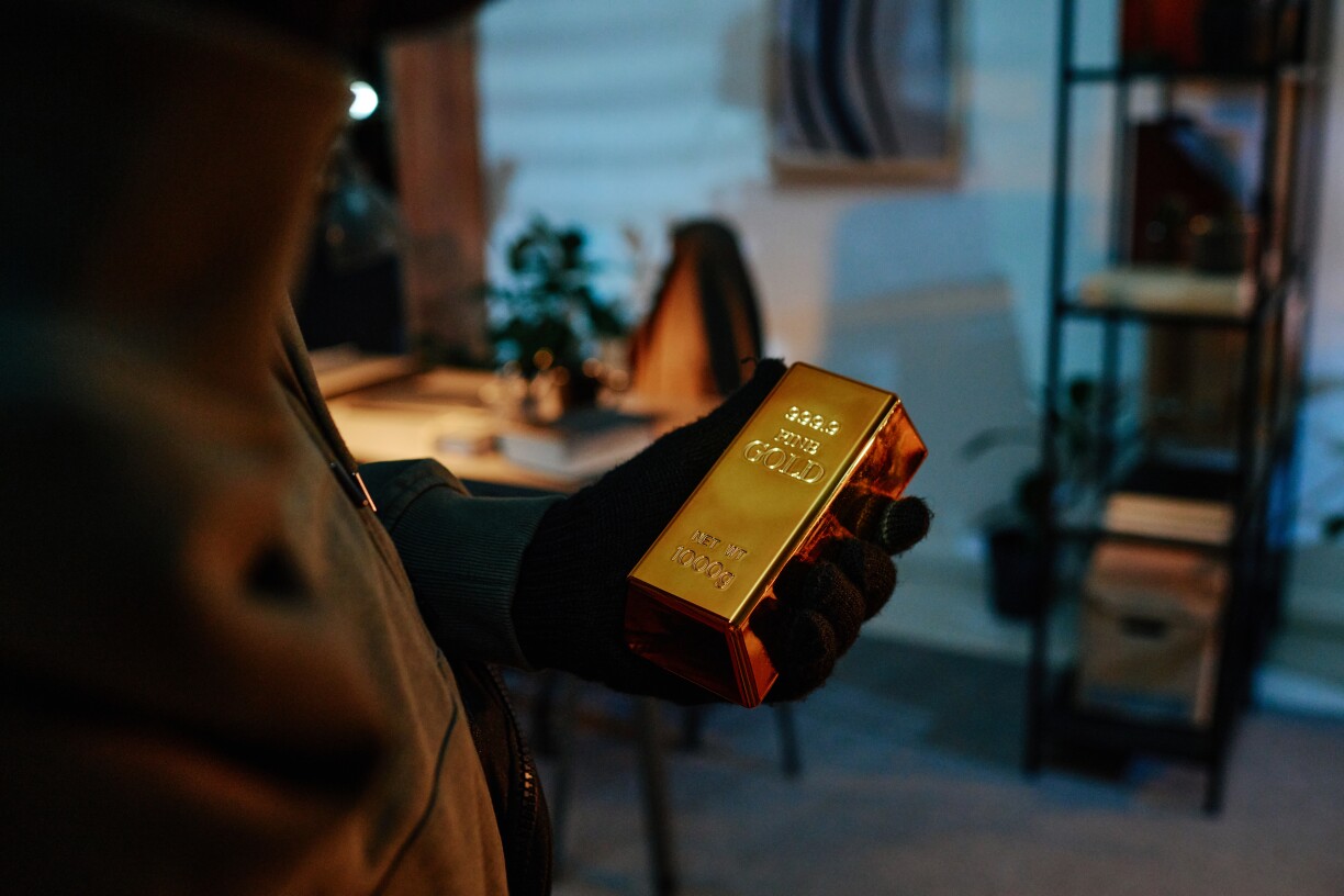 Symbolbild vun engem Abriecher, deen e Goldbarre klaut.