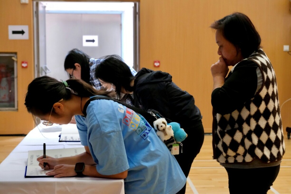 Mourners write in books as they pay their respects at a memorial point in Tai Po district