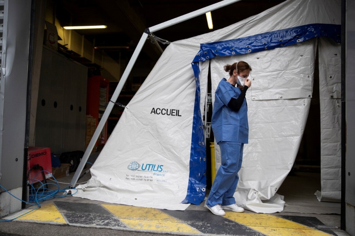 Une membre du staff médical ajuste son masque avant d'entrer dans une tente installée dans la cour de l'hôpital Henri Mondor à Créteil