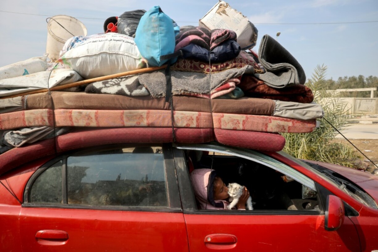A displaced Palestinian child playes with a kitten in a car on Salah al-Din road in Nuseirat as people make their way to the north of the Gaza Strip