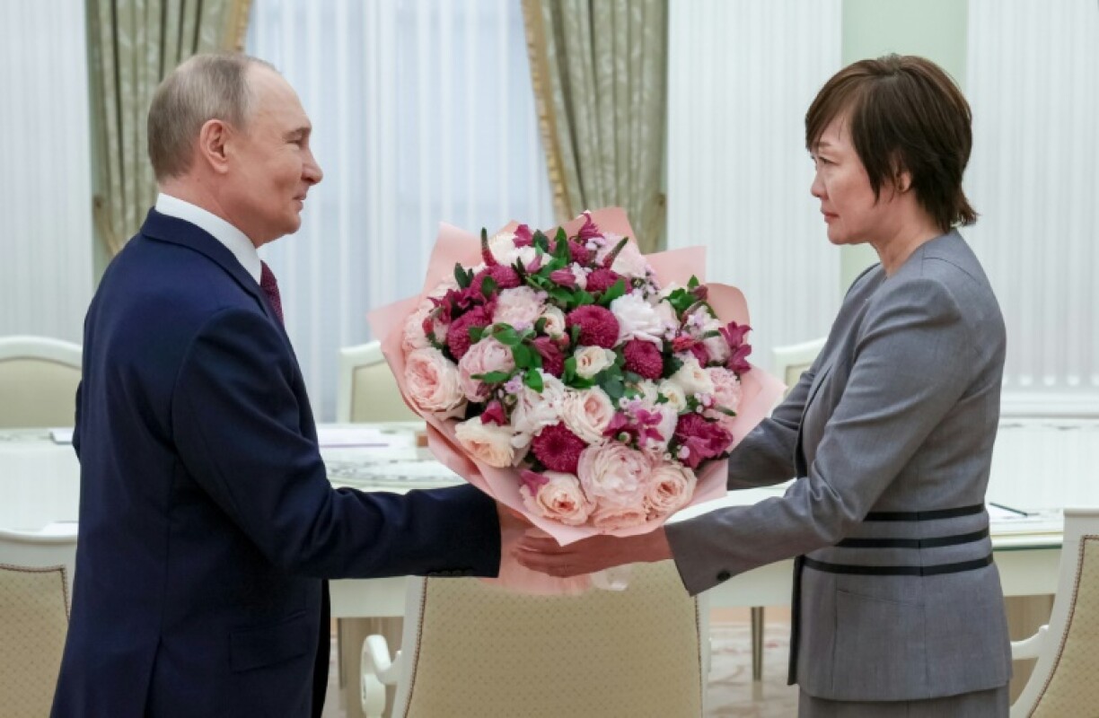 In this pool picture distributed by the Russian state agency Sputnik, Russia's President Vladimir Putin gives a bunch of flowers to Akie Abe, widow of former Japanese premier Shinzo Abe, at the Kremlin