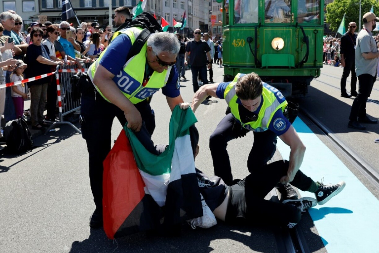 Police officers remove a protestor holding a Palestinian flag
