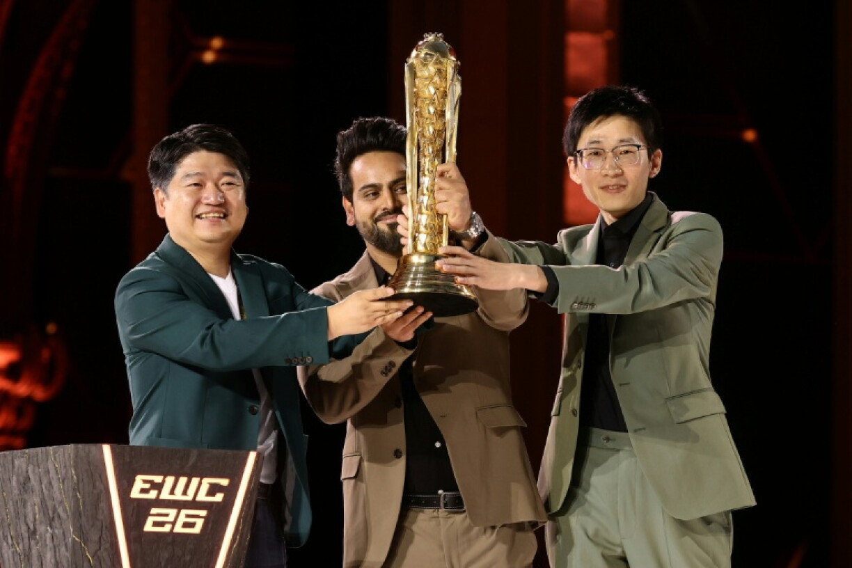 Le dirigeant de l'équipe chinoise All Gamers Le Kedeng (à gauche) brandit le trophée de l'Esports World Cup à Paris le 23 août 2026