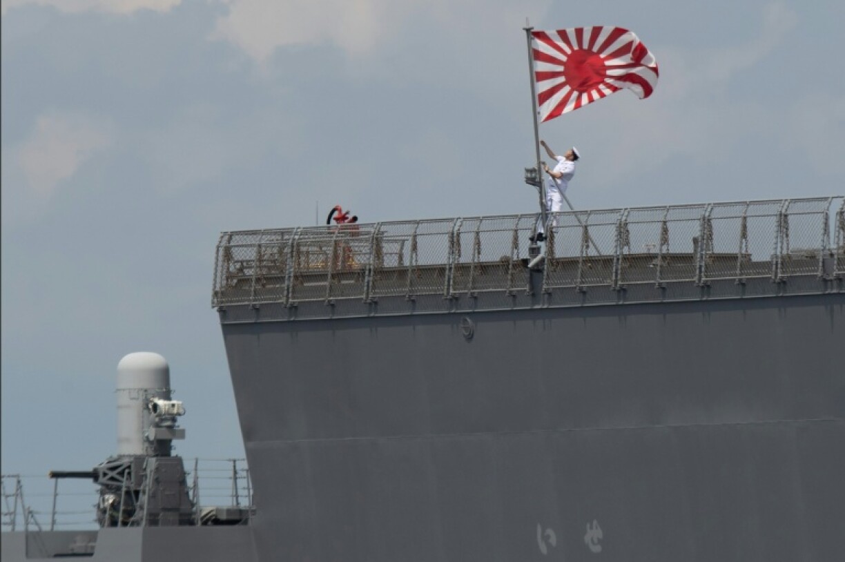 Un marin hisse le pavillon des Forces maritimes d'autodéfense japonaises à bord du JS Ise, un destroyer porte-hélicoptères de classe Hyuga, lors de son arrivée au port international de Manille, le 21 juin 2025 aux Philippines