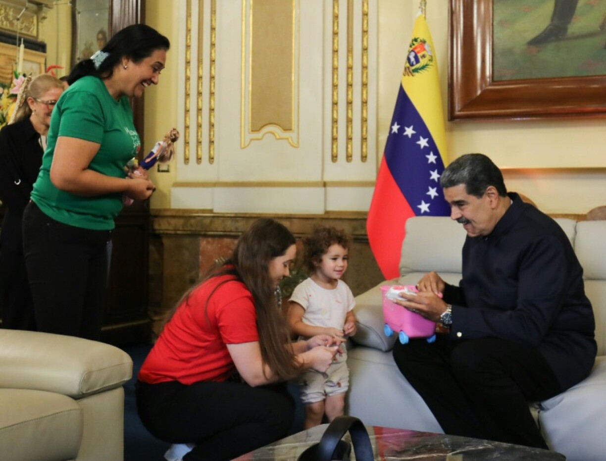 Handout picture released by Venezuela's presidency showing President Nicolas Maduro (R) with Yorelys Bernal (C) and her daughter Maikelys Espinoza after the girl's return from the United States, where she was kept after her parents' deportation