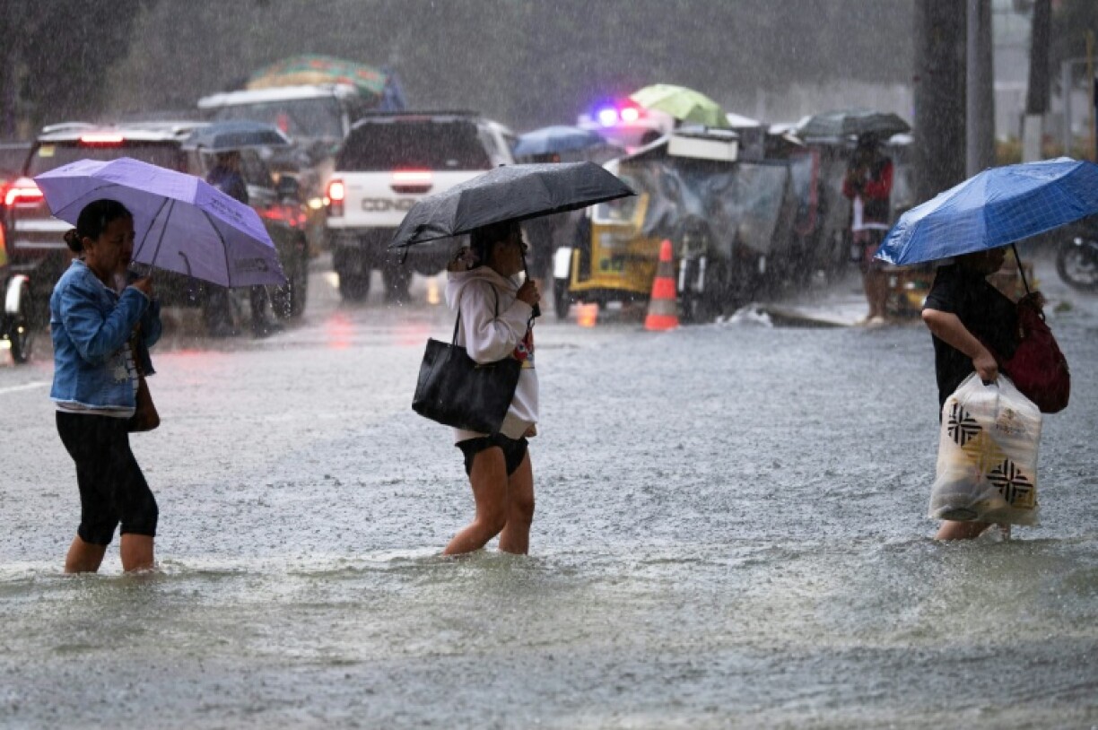 People wade through a flooded street in the Philippine capital Manila after heavy rains that displaced thousands