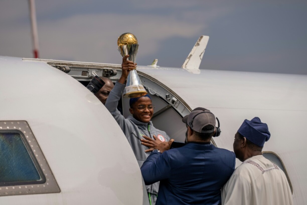 Nigeria's Rasheedat Ajibade holds the Women's Africa Cup of Nations (WAFCON) trophy as she emerges from the plane carrying the Super Falcons at the Nnamdi Azikiwe International Airport in Abuja