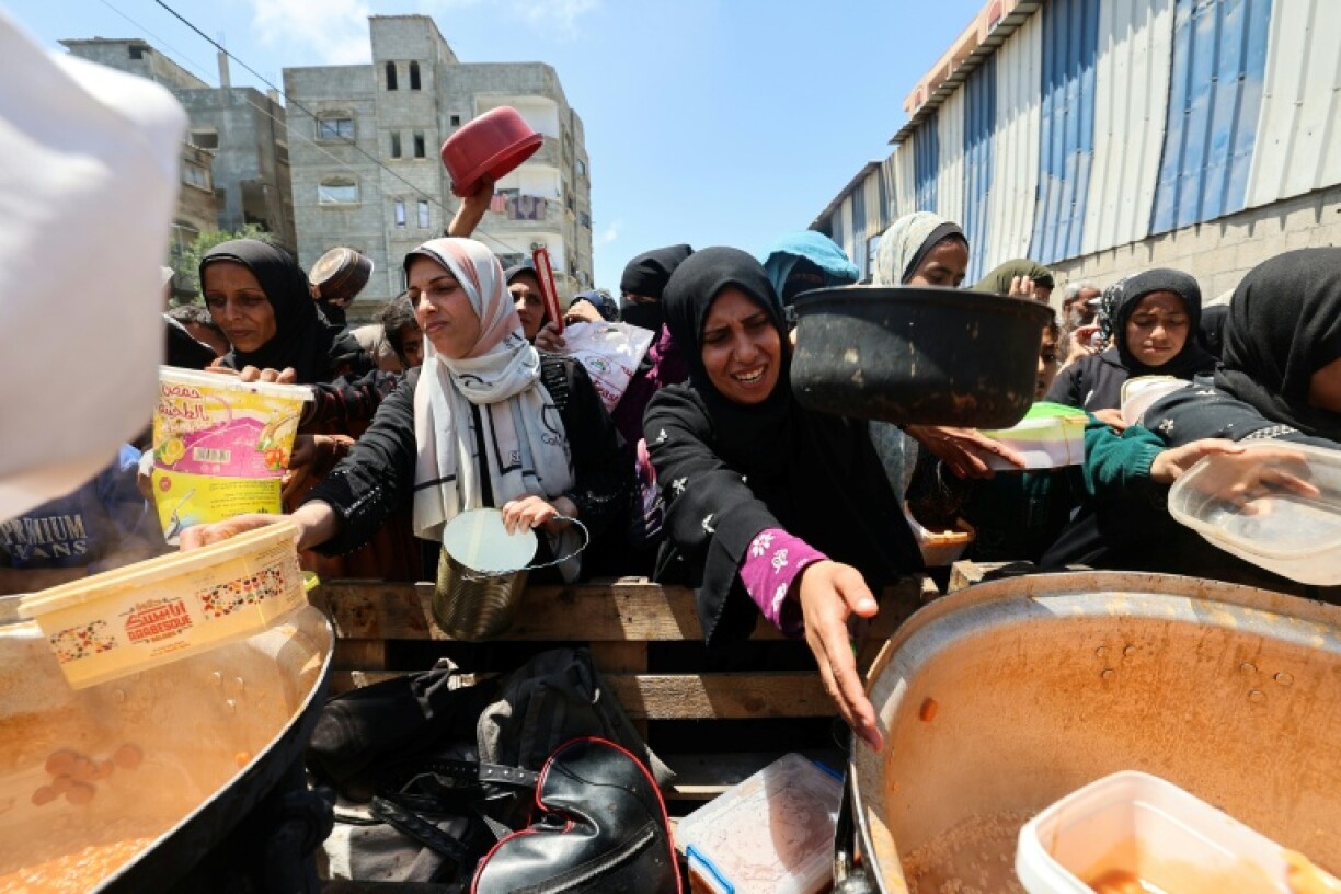Palestinians queue for food distributed by a charity kitchen at the Nuseirat refugee camp in central Gaza