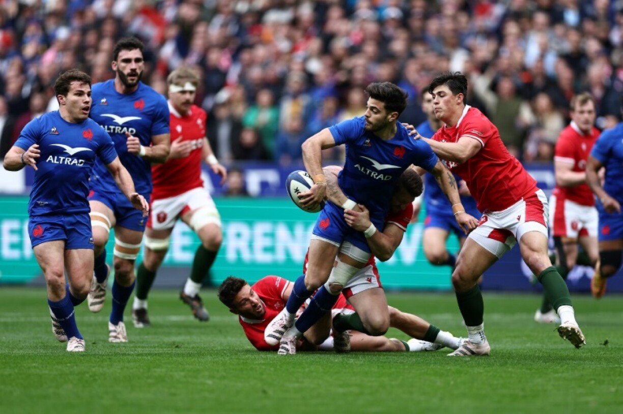 Le demi d'ouverture du XV de France Romain Ntamack (C) s'apprête à passer le ballon au demi de mêlé Antoine Dupont (G) lors d'un match du Tournoi des six nations contre le pays de Galles, le 18 mars 2023 à Saint-Denis