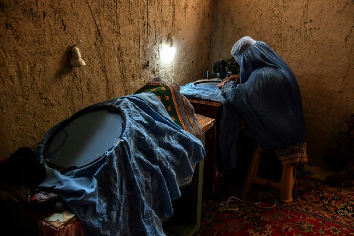 A lady sews a burqa: it has long roots in Afghanistan, and was strictly enforced during the first period of Taliban government rule