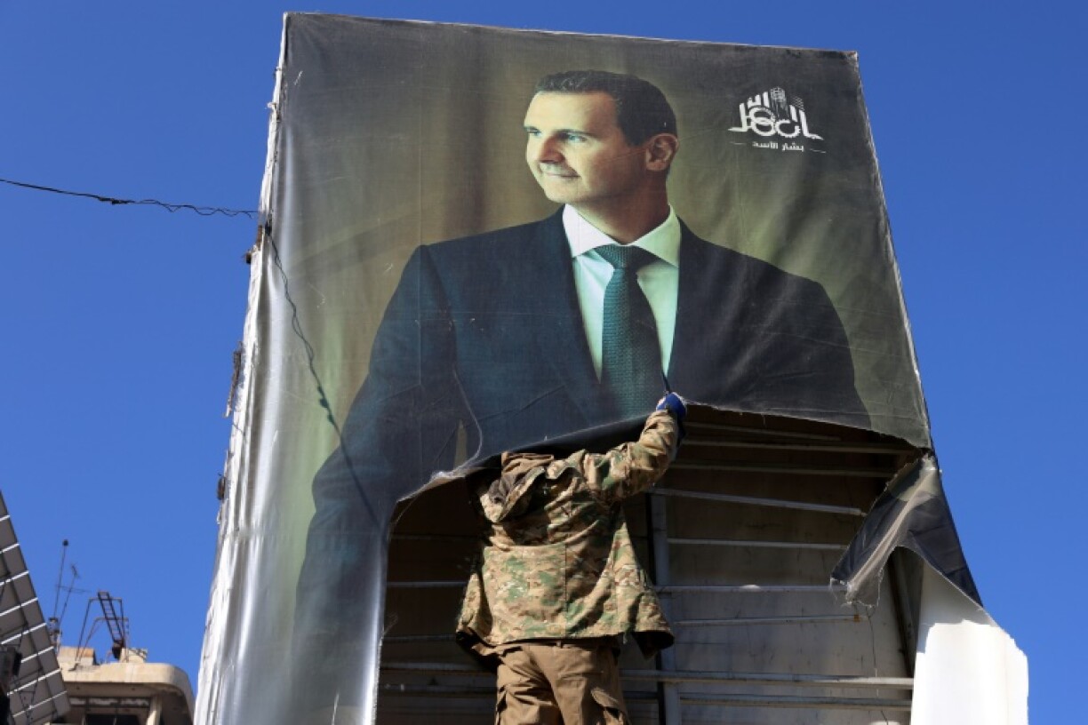 A rebel tears down a picture of Assad in Aleppo