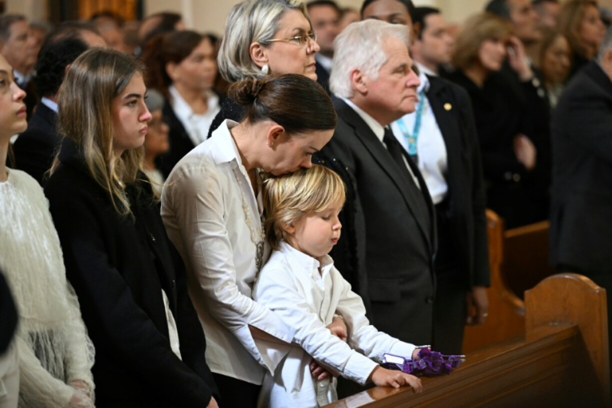 Uribe's window, Maria Claudia Tarazona, prays with her son during the funeral mass