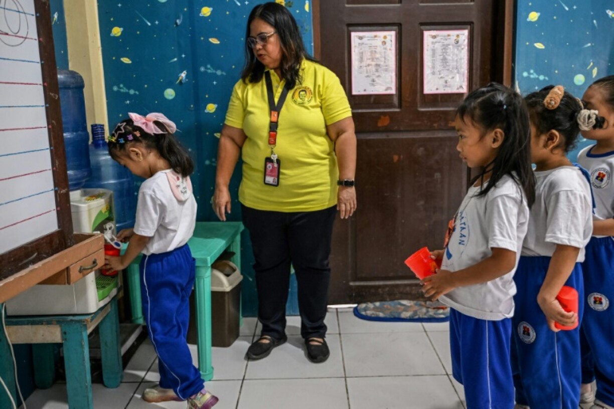 Teacher Lolita Akim with her students during a water break at an elementary school at Baseco in Manila on March 21