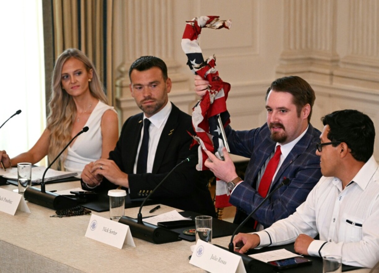 L'influenceur conservateur Nick Sortor exhibe un drapeau américain brûlé lors d'une table ronde sur le mouvement Antifa, le 8 octobre 2025 à la Maison Blanche, à Washington