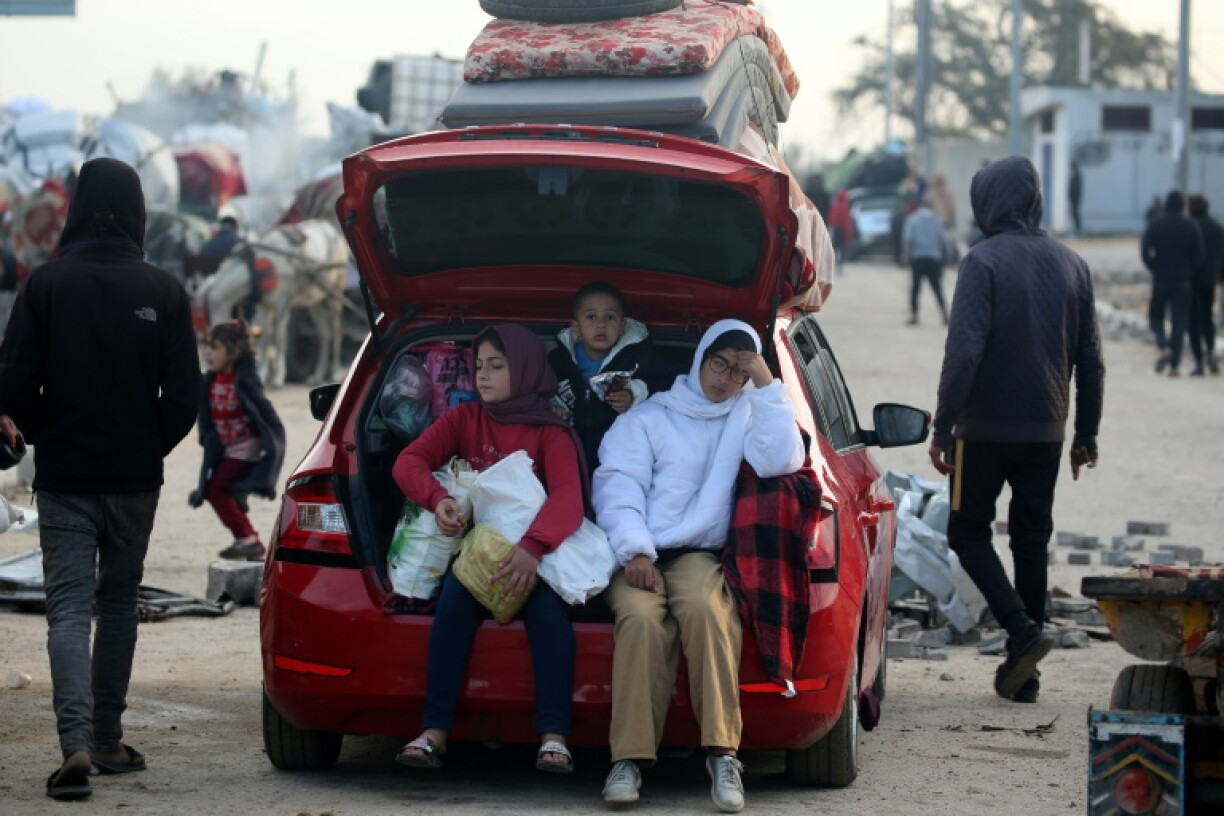 Displaced Palestinians wait along the Salah al-Din road in Nuseirat near the blocked Netzarim Corridor, unable to cross into northern Gaza
