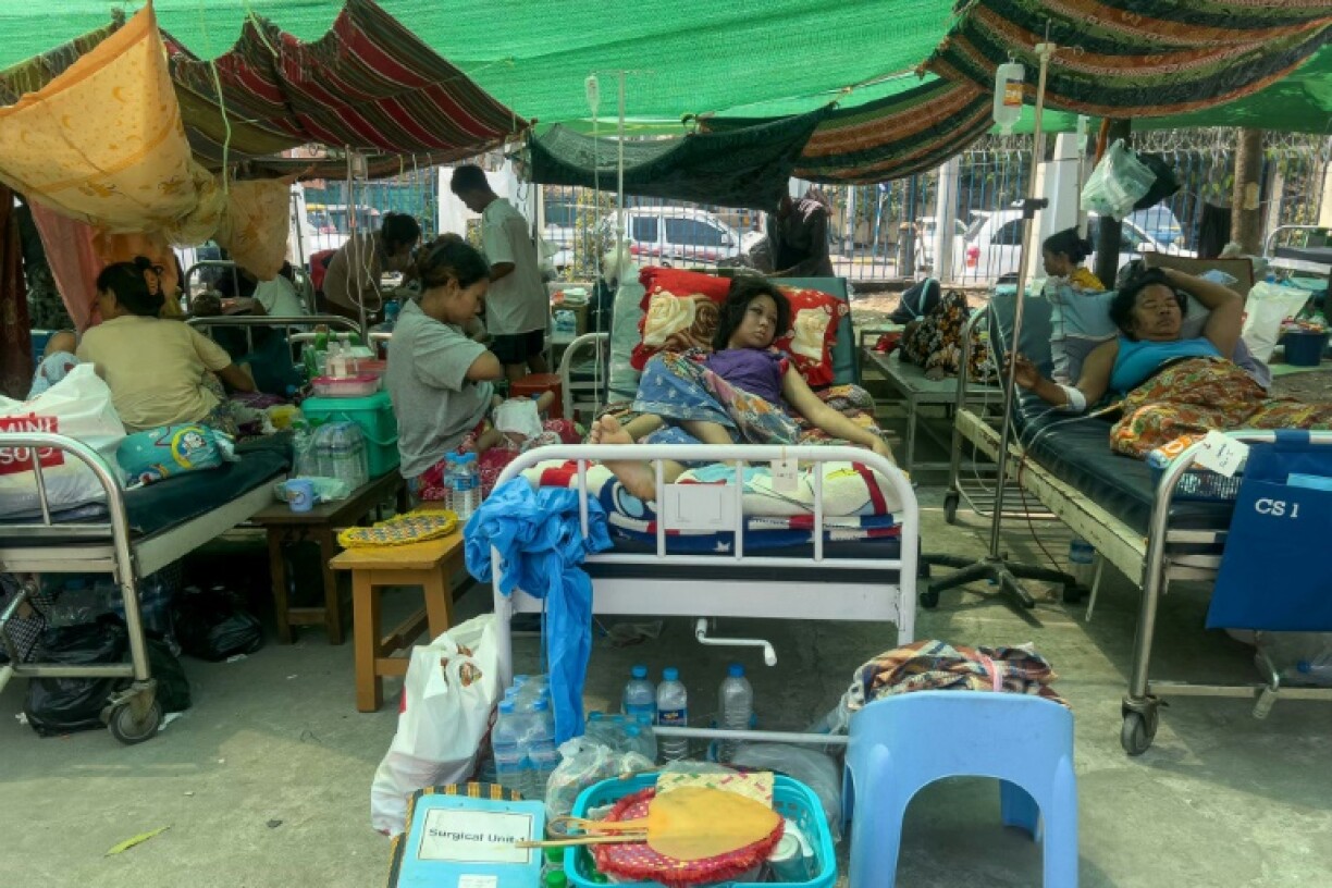 Hundreds of patients, including babies, the elderly and Buddhist monks, lie on gurneys in a hospital car park in the sweltering heat of Mandalay