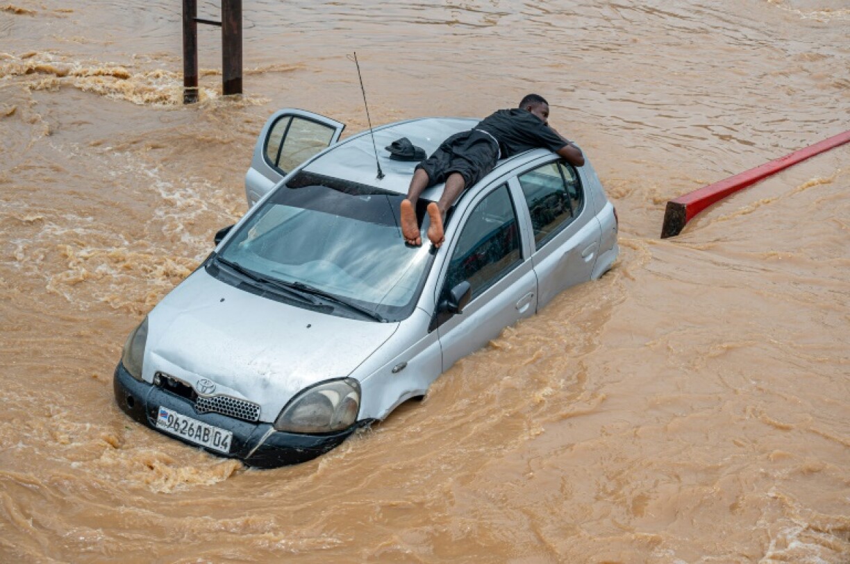 A man lies on top of a car amid rising floodwaters in Kinshasa