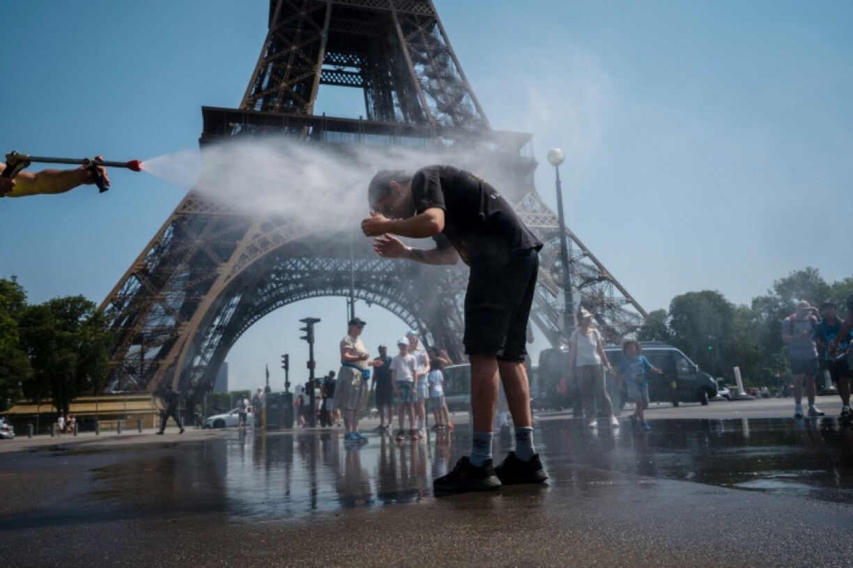 A municipal employee sprays water to cool off tourists in front of the Eiffel Tower in Paris, on July 2, 2025, as a heatwave hits France