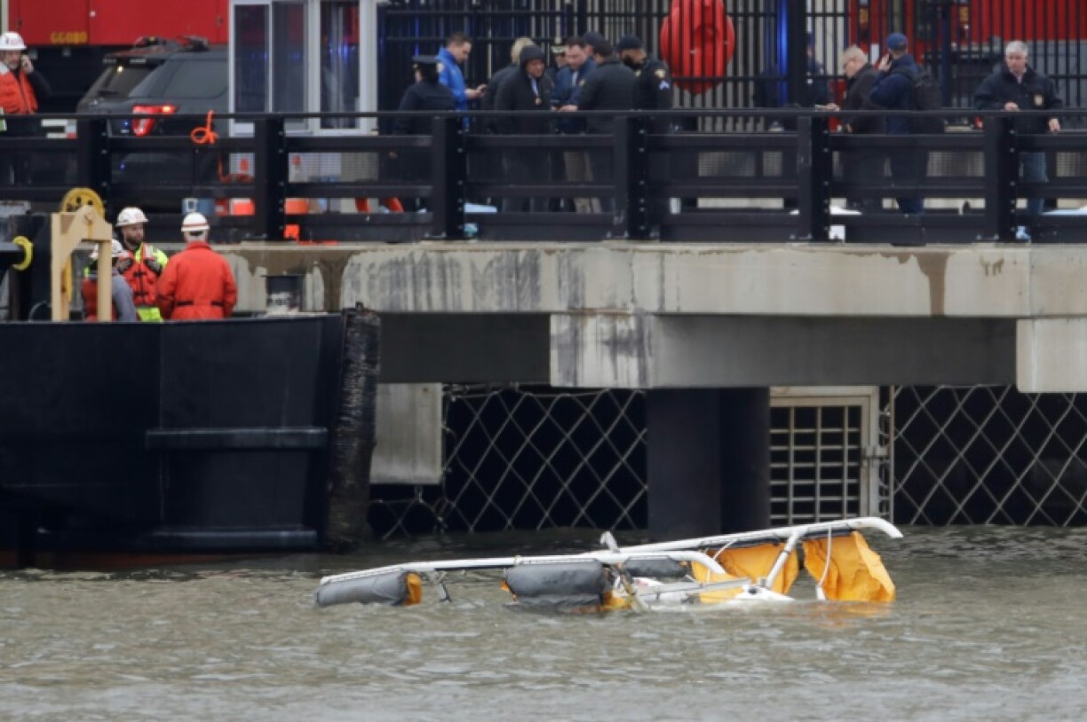 First responders are seen near the landing skids of a helicopter after it crashed into the Hudson River
