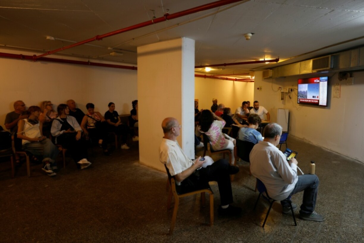 People watch news updates inside a bomb shelter in the Israeli city of Haifa