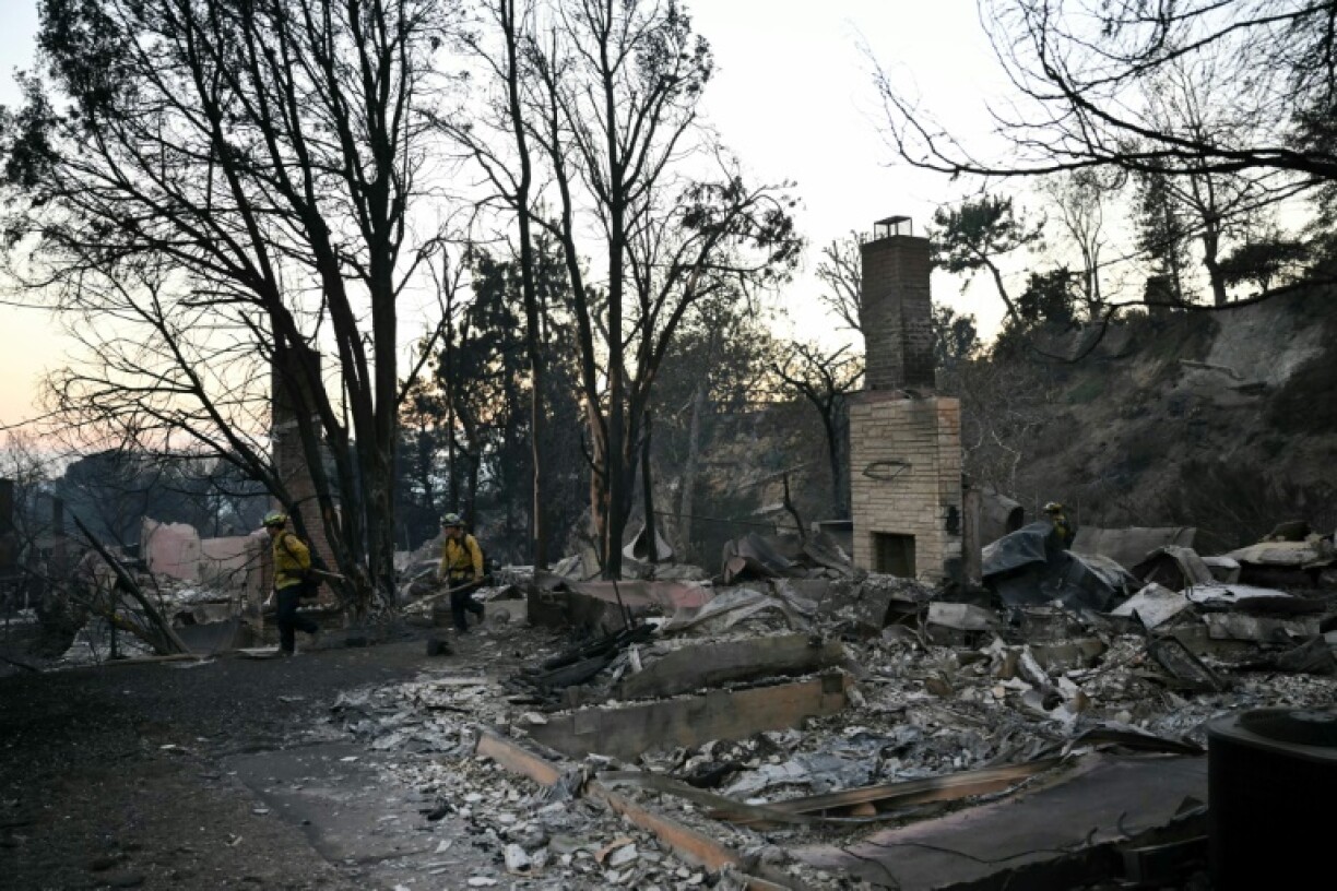 Firefighters walk through destroyed homes turning off gas valves as the Eaton Fire continued to burn in Altadena, California on January 10, 2025