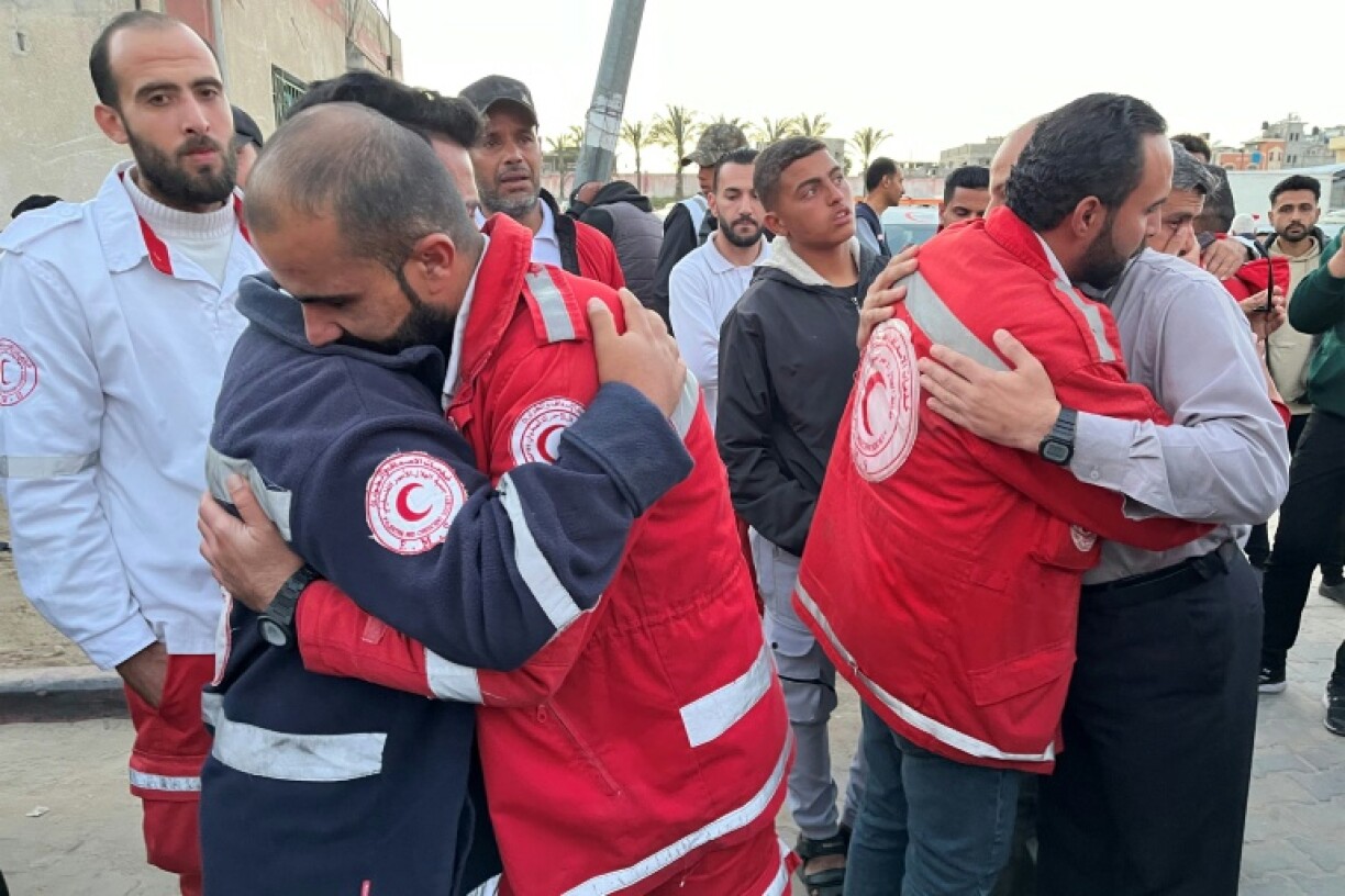 First responders embrace as the bodies of 15 colleagues killed in a March 23 ambush by the Israeli army are delivered to a hospital in Khan Yunis.