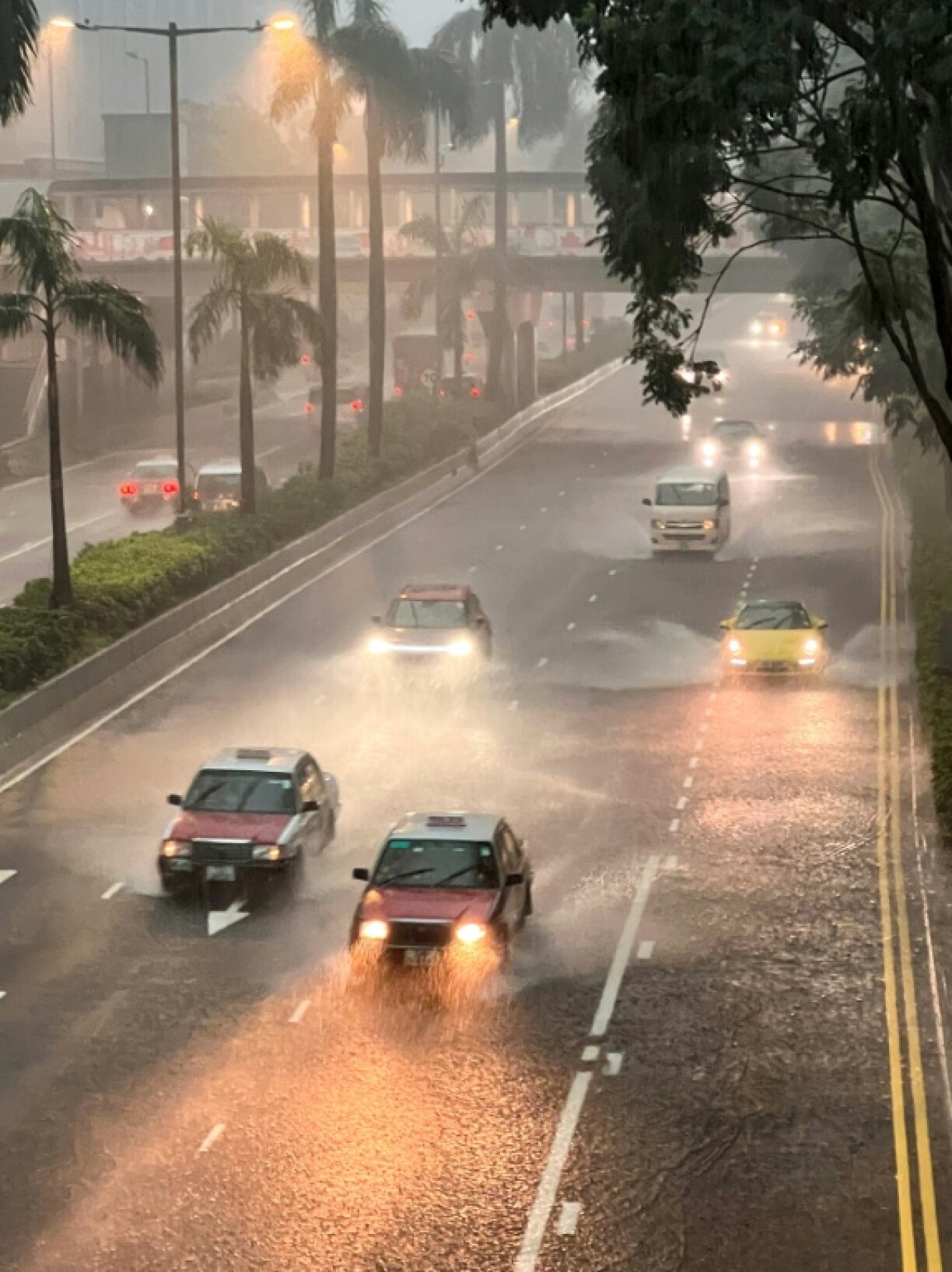 Taxis and other vehicles drive along a waterlogged Gloucester Road in Hong Kong's Wanchai district on August 5, 2025, amid a black rainstorm warning issued by the city's weather observatory