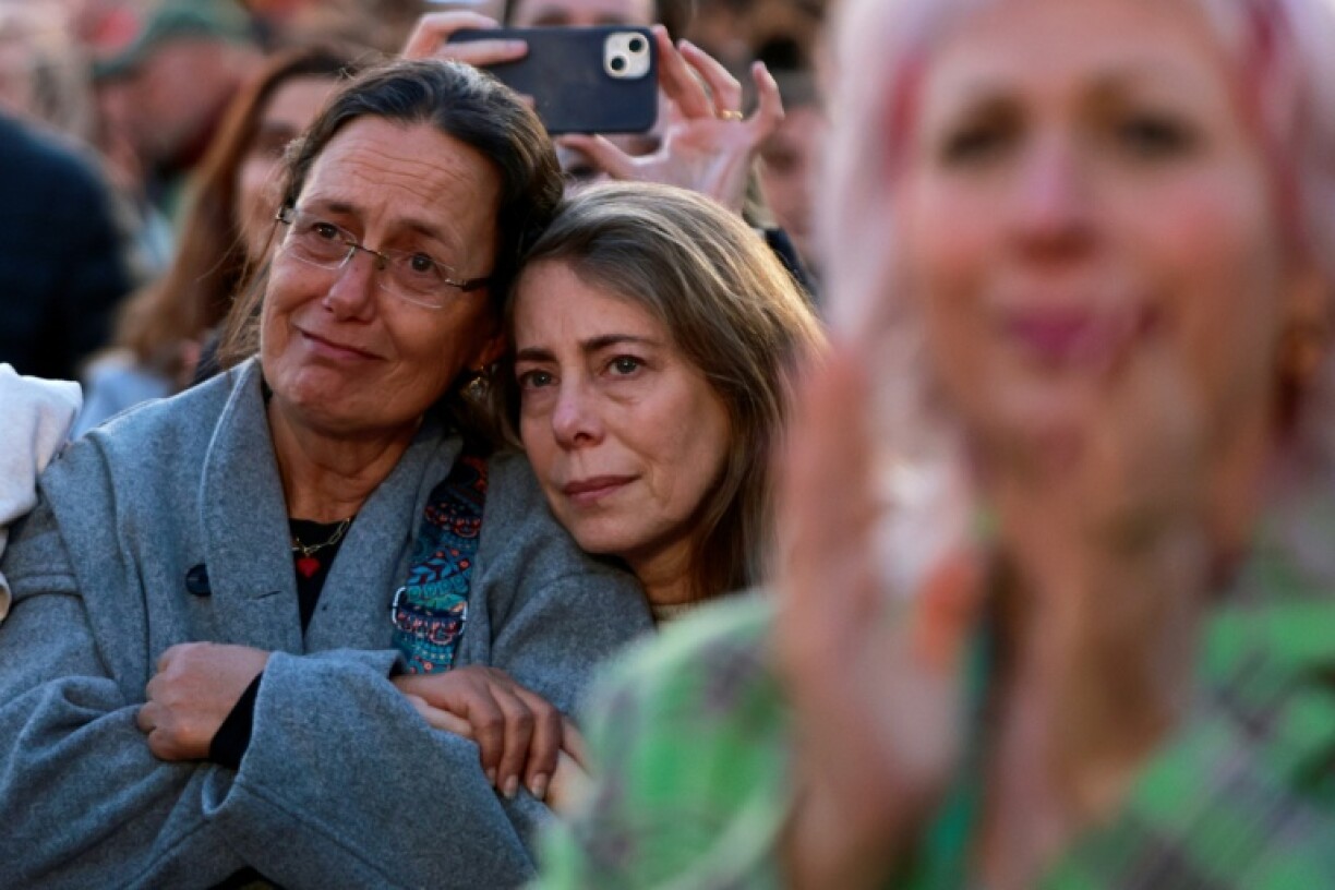 Deux femmes s'enlassent en regardant une émission de télévision en direct sur la libération des trois otages israéliennes, sur la