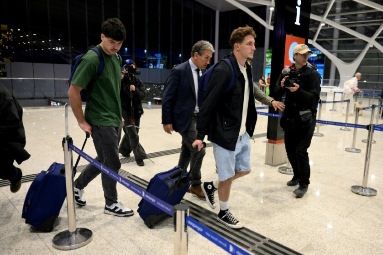 Les joueurs de rugby français Hugo Auradou (G) et Oscar Jegou (2e à droite) et leur avocat Rafael Cuneo Libarona (C), à l'aéroport international d'Ezeiza, dans la province de Buenos Aires, en Argentine, le 3 septembre 2024