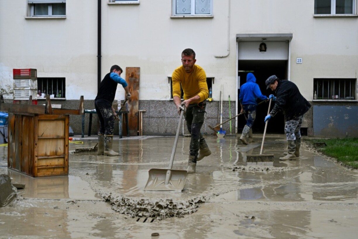 Des habitants nettoient la boue dans une cour après des inondations à Faenza, le 19 mai 2023 dans la région d'Emilie-Romagne, dans le nord de l'Italie
