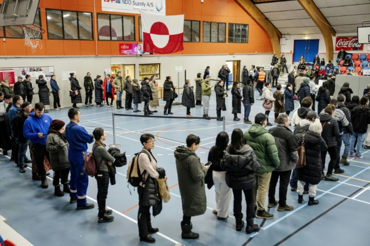 Un drapeau aux couleurs nationales du Groenland est déployé alors que les gens font la queue pour voter à Nuuk, au Groenland, le 11 mars 2025