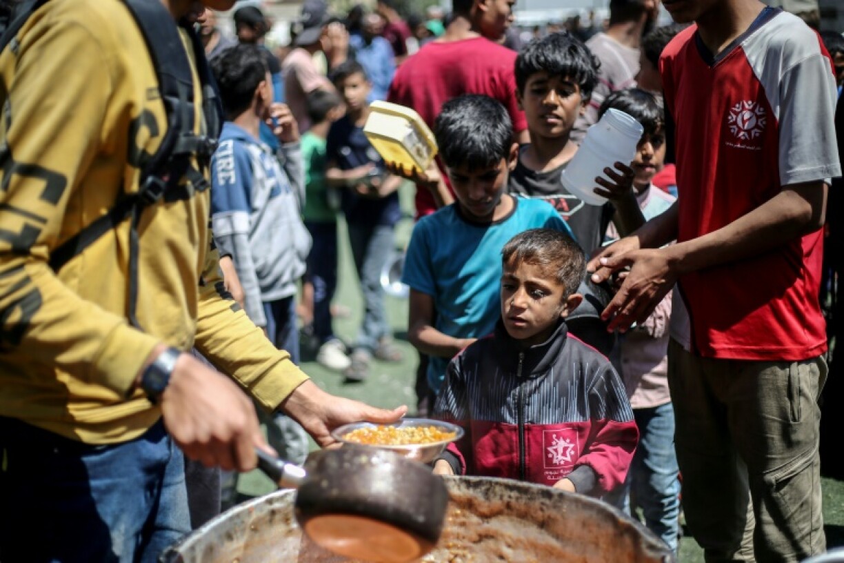Des Palestiniens font la queue pour une distribution de nourriture dans le camp de réfugiés de Nousseirat, dans le centre de la bande de Gaza, le 19 avril 2025