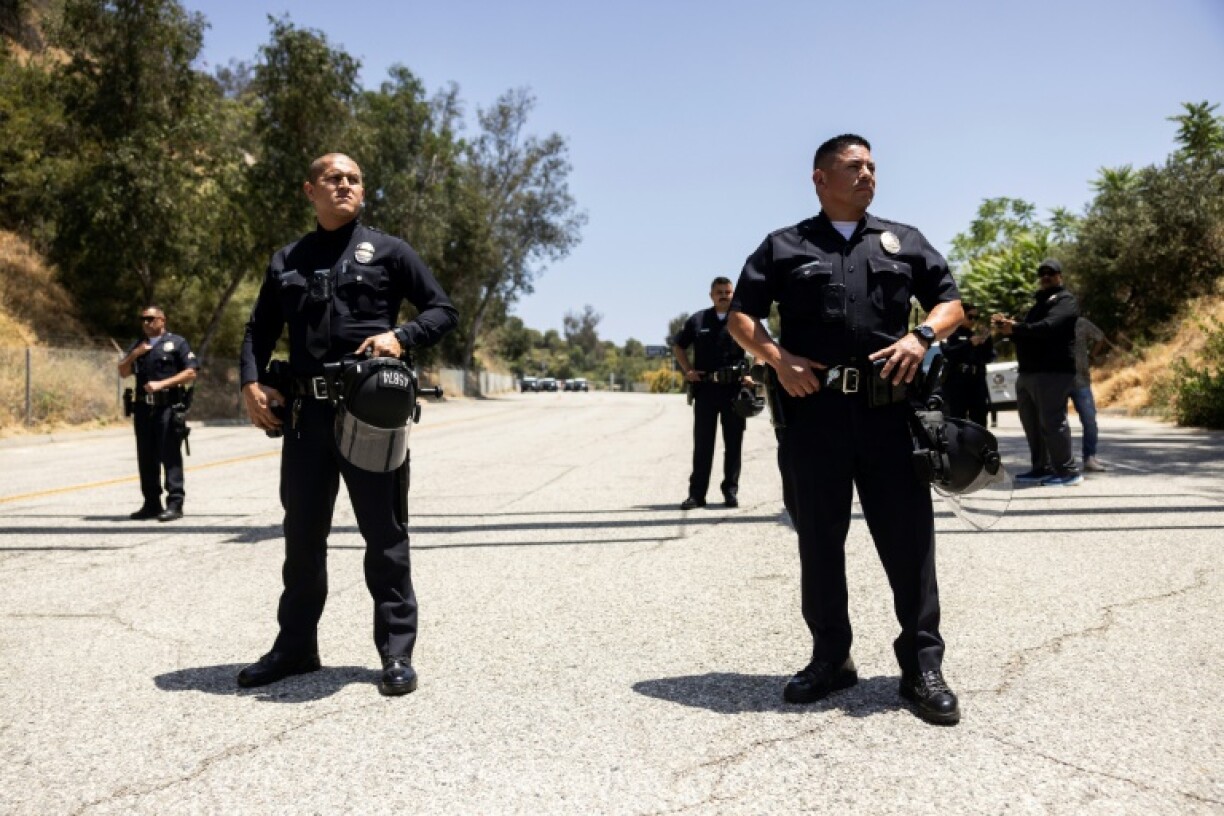 Los Angeles police stand guard as protesters gather in front of one of the parking lot entrances at Dodgers Stadium, where federal immigration agents were denied entry