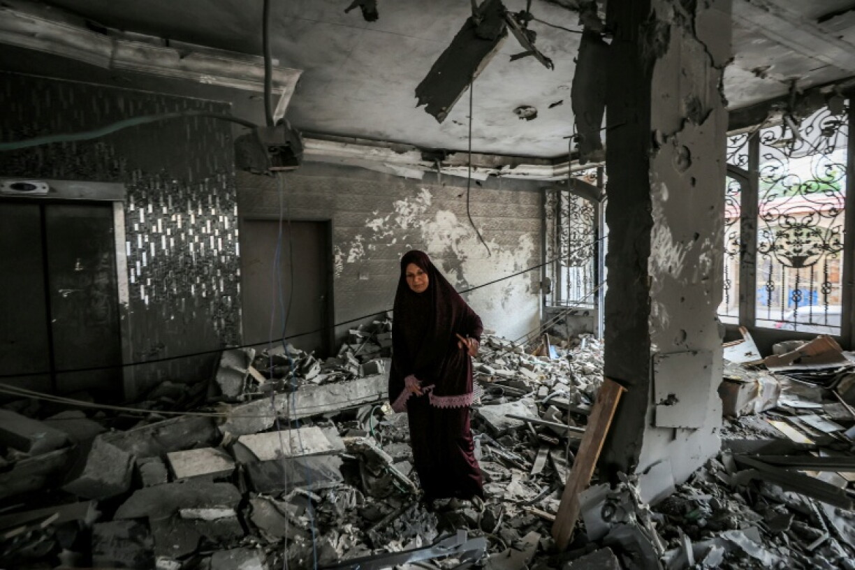 A woman inspects debris in a heavily damaged apartment building following an Israeli strike in Gaza City that Israel said targeted the top Hamas leader in the territory