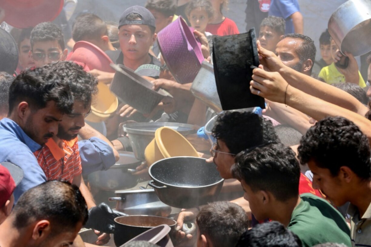 Palestinians try to get food at a charity kitchen providing hot meals in Gaza City