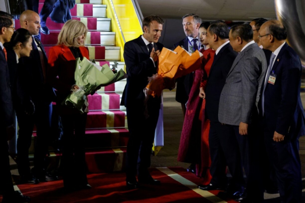 France's President Emmanuel Macron (C) and his wife Brigitte Macron (in red) are greeted by Vietnamese officials upon their arrival at Noi Bai International Airport in Hanoi