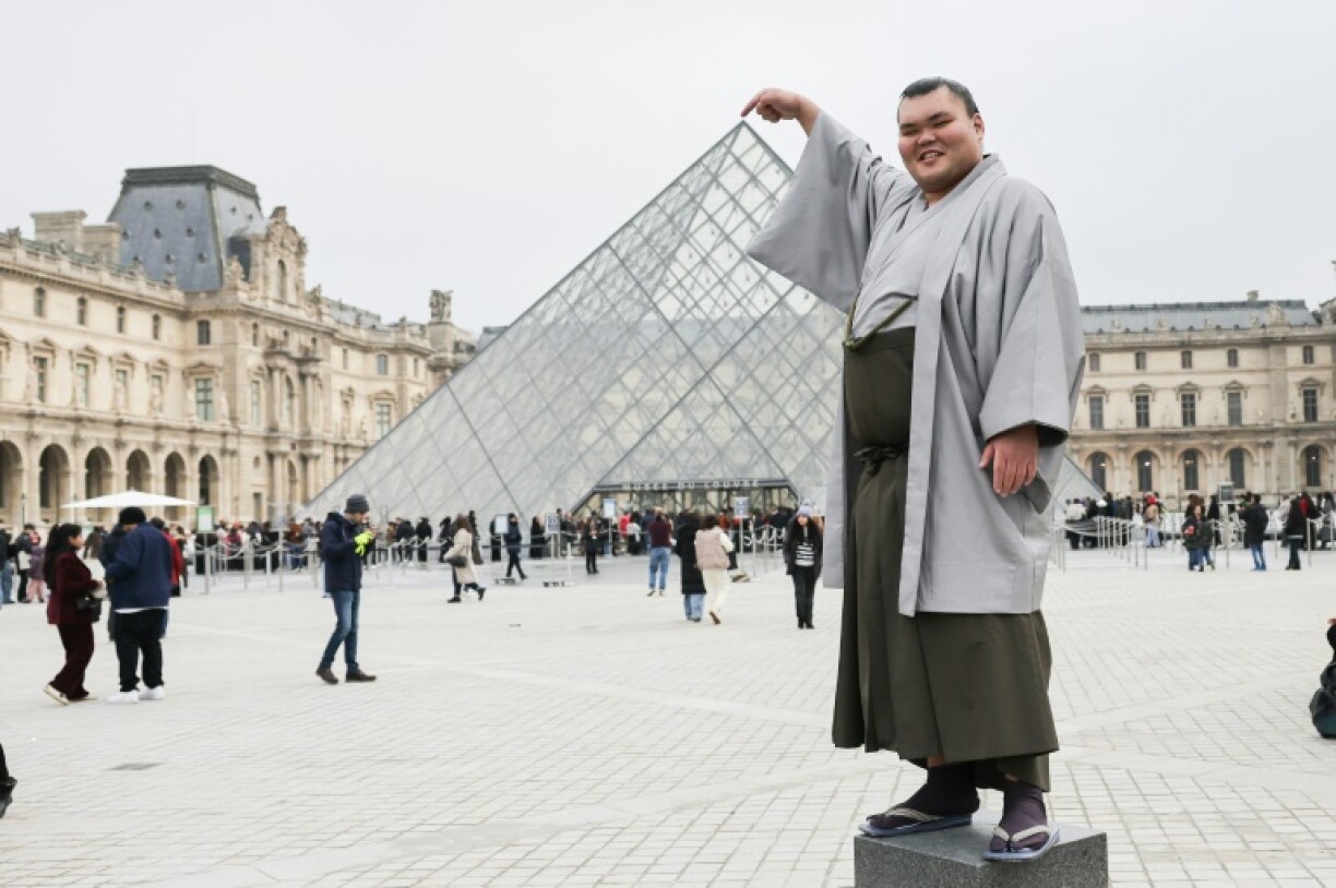 Tochitaikai Yu poses for a photo in front of the Louvre Pyramids in Paris