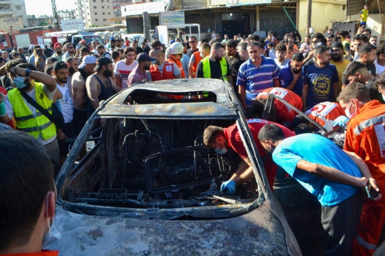 Paramedics inspect a burnt vehicle, which was targeted in an Israeli airstrike, in the Ayrouniyeh area near Lebanon's northern port city of Tripoli on July 8, 2025
