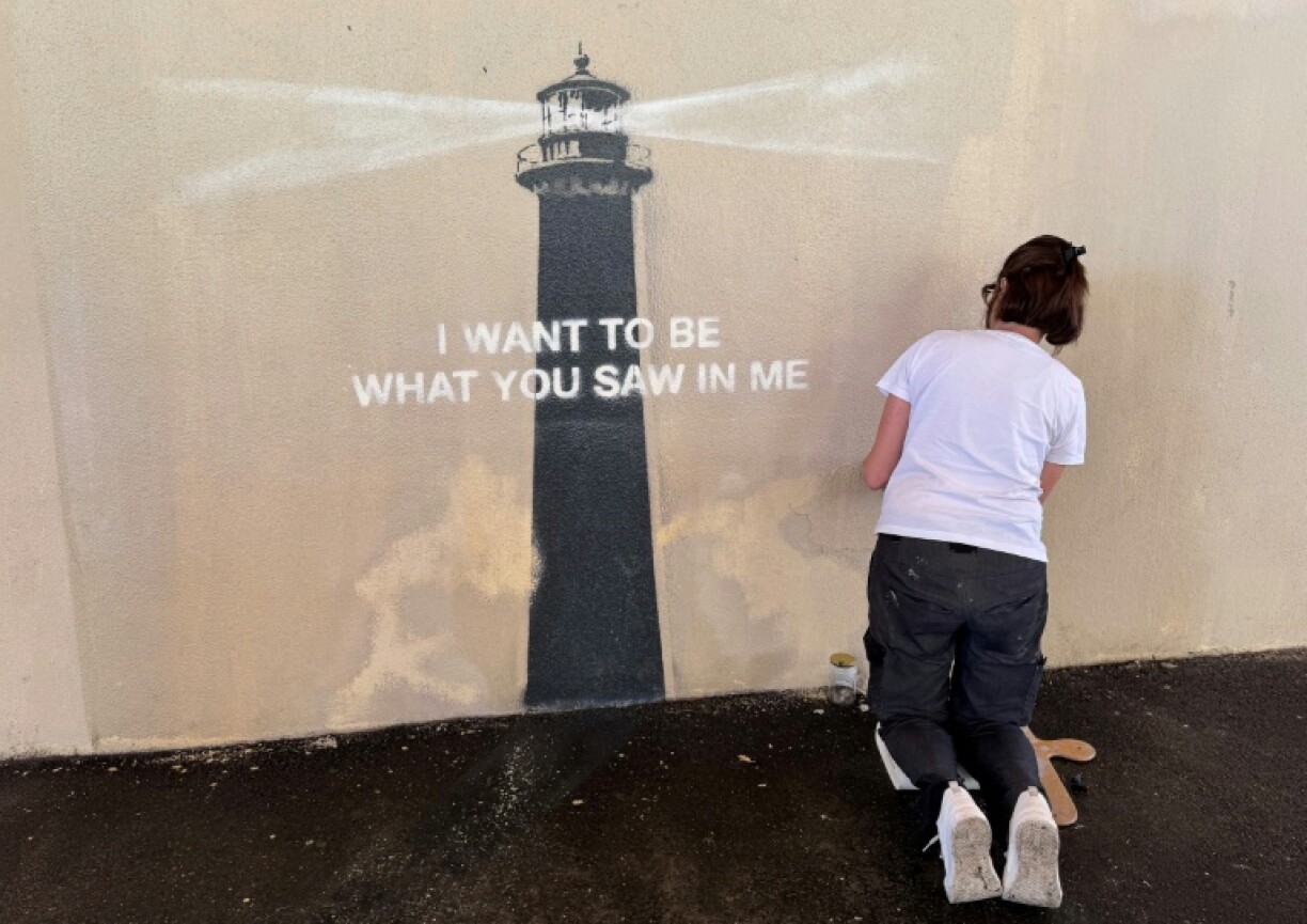 Agnès Perrone, peintre en décor du patrimoine, répare une œuvre d'art de l'artiste de rue Banksy représentant un phare sur la façade d'un bâtiment, après qu'elle a été vandalisée pendant la nuit à Marseille, le 1er juin 2025
