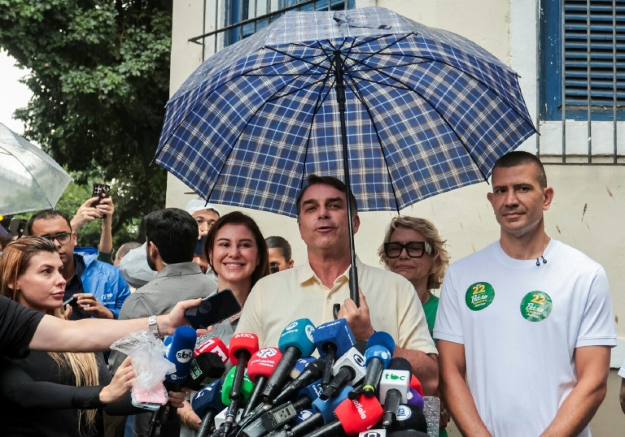 Le candidat à la présidence du Brésil, Flavio Bolsonaro, s'adresse aux journalistes aux côtés de son épouse Fernanda Bolsonaro (G) et de sa mère Rogeria Bolsonaro (2e à D, derrière), après avoir voté lors du second tour de l'élection présidentielle à Rio de Janeiro, au Brésil, le 25 octobre 2026